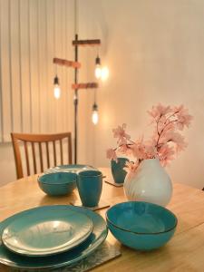 einen Holztisch mit blauen Gerichten und eine Vase mit Blumen in der Unterkunft Cosy Prenton home near Tranmere Club and Liverpool in Birkenhead
