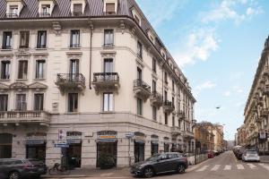 um grande edifício branco com carros estacionados na frente dele em Primopiano - Ugo Bassi em Milão