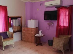 a purple room with a tv and a table and chairs at the FARMHOUSE BOUTIQUE GUESTHOUSE AND BEERGARDEN CC in Outjo