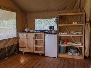 a kitchen in a tent with a refrigerator and shelves at Safaritent Suikerpeer in Ruinerwold