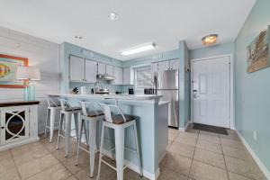 a kitchen with blue walls and white cabinets and bar stools at Bring Your Boat! 2br/2ba Condo on the Bay! in Orange Beach