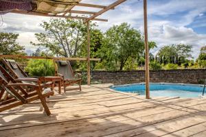 eine Holzterrasse mit Stühlen und einem Pool in der Unterkunft Skippers - Adults only in Ukunda