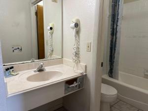 La salle de bains est pourvue d'un lavabo, d'un miroir et de toilettes. dans l'établissement Sunset Inn and Suites, à Fredericksburg