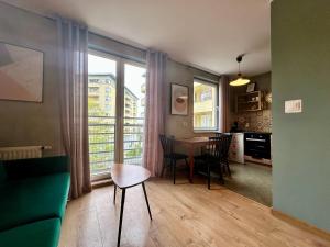 a living room with a table and chairs and a kitchen at Apartament Szafranowy in Wrocław