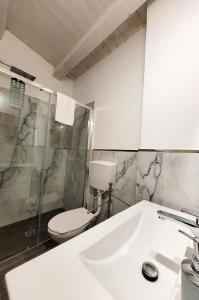 a white bathroom with a toilet and a sink at B&B Loft Famiglia Arezzo in Ragusa