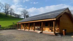 a house with a solar roof on top of it at Cherry Cabin - Little Log Cabin in Wales in Bettws Cedewain
