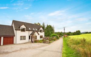 a white house with a garage on a road at 5-Bed Highland Lodge - NC500 - Sleeps 10 in Alness