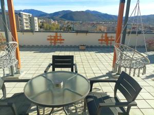 einen Glastisch und Stühle auf dem Balkon in der Unterkunft Penthouse City View Infinity in Braşov