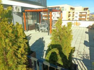 eine Terrasse mit einem Tisch, Stühlen und Bäumen in der Unterkunft Penthouse City View Infinity in Braşov
