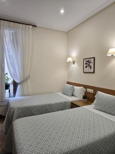 a hotel room with two beds and a window at Pensión San Jerónimo in San Sebastián