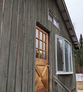 ein Holzgebäude mit einer Tür und einem Fenster in der Unterkunft Meadowlark Cabin #5 in Maynooth