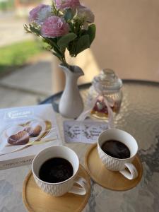 due tazze di caffè sedute su un tavolo con fiori di Smeštaj Vrhovac a Vrdnik