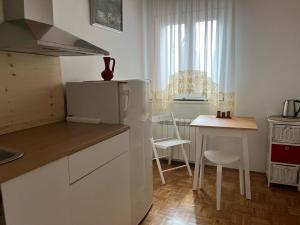 a kitchen with a small table and a white refrigerator at ArtWoodResidence in Ankaran