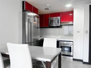 uma cozinha com armários vermelhos e uma mesa e cadeiras brancas em Linda vista al río. Seguridad y Parqueo em Guayaquil