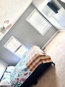 1 dormitorio con 2 ventanas y 1 cama con manta en Home with Nance, en Oshawa