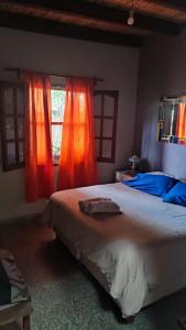 a bedroom with a large bed with orange curtains at Casa Manipa -3 dormitorios in Cafayate