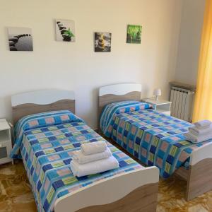 2 łóżka w sypialni z ręcznikami w obiekcie Nella’s home w mieście Gavi