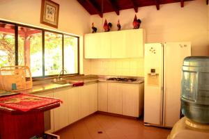eine Küche mit weißen Schränken und einem weißen Kühlschrank in der Unterkunft Villas Mamilú. entrada y salida cien por ciento flexible in Santa Fe de Antioquia