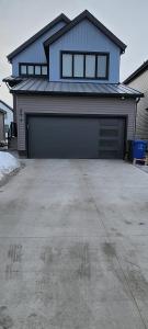 a house with two garage doors in a driveway at Entire Basement Suite with Private Entrance in Winnipeg