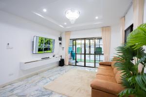 a living room with a couch and a tv at Di Pool Villa Hunhin 2km from beach in Hua Hin