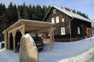 un coche aparcado frente a un granero en la nieve en Schöne Wohnung in Klingenthal mit Garten, Grill und Terrasse en Klingenthal