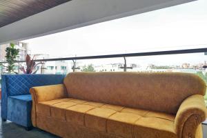 a brown couch sitting in a room with a large window at OYO Collection O Hotel Rk Inn in Pune