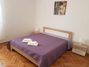 - une chambre avec un lit violet et 2 serviettes dans l'établissement Apartments and rooms Iva, à Pag