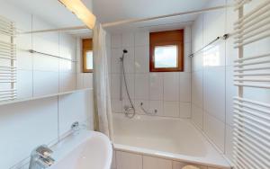 Baño blanco con bañera y lavamanos en Surpunt 44 en St. Moritz