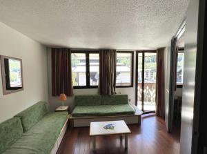 sala de estar con sofá verde y ventanas en L'Aiguille - maeva Home - 2 Pièces 5 Personnes Confort 76 en Chamonix-Mont-Blanc