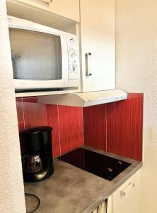 una cocina con microondas sobre una barra en L'Aiguille - maeva Home - 2 Pièces 5 Personnes Confort 76 en Chamonix-Mont-Blanc