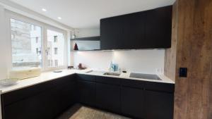 a kitchen with black cabinets and a sink and a window at Paravicini 5 in St. Moritz