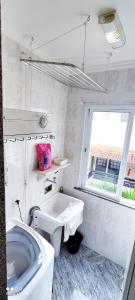 a bathroom with a toilet and a sink and a window at Ap a 50m da Prainha em Arraial in Arraial do Cabo