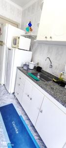 a white kitchen with a sink and a refrigerator at Ap a 50m da Prainha em Arraial in Arraial do Cabo