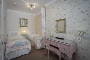 a bedroom with two beds and a desk with a mirror at The Wescoe Guesthouse in Blackpool