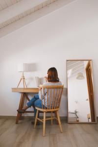 a woman sitting in a chair at a desk with a mirror at Pure Fonte Velha B&B in Vila do Bispo