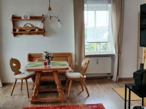 d'une salle à manger avec une table, des chaises et une fenêtre. dans l'établissement Herzlich Willkommen im Vier Jahreszeiten Gäste Apartments Bad Steben, à Bad Steben