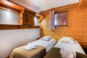dwa łóżka w pokoju z drewnianymi ścianami w obiekcie Résidence Les Alpages de Chantel - maeva Home - Appartement 4 Pièces 8 Personnes - Sélection MAE-1649 w mieście Bourg-Saint-Maurice