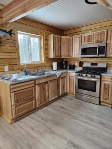 a kitchen with wooden cabinets and a stove top oven at Red Salmon Retreat, Cabin 8 at Lower Kenai Lodge in Kenai +62 photos