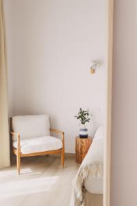 a white room with a chair and a plant at Pure Fonte Velha B&B in Vila do Bispo