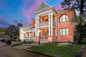 a large red brick house with white columns at Cripple Creek Hospitality House & Travel Park in Cripple Creek
