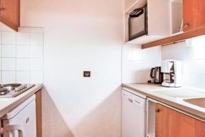 una pequeña cocina con armarios blancos y fregadero en Quartier Crève Cœur - maeva Home - 2 Pièces 5 Personnes Confort 07 en Valmorel