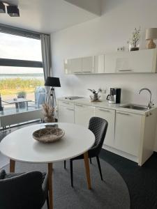 eine weiße Küche mit einem Tisch und Stühlen in der Unterkunft Doppelzimmer im Strandhaus 2 in Elsterheide