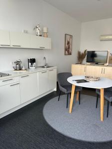 eine Küche mit weißen Schränken sowie einem Tisch und Stühlen in der Unterkunft Doppelzimmer im Strandhaus 2 in Elsterheide