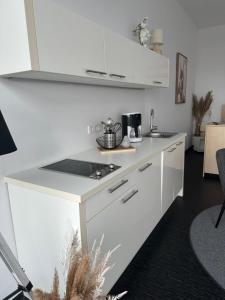 eine Küche mit weißen Schränken und einer Arbeitsplatte in der Unterkunft Doppelzimmer im Strandhaus 2 in Elsterheide