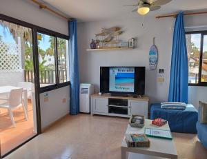 sala de estar con TV de pantalla plana y sofá en Casa Del Mar - Corralejo Playa, en Corralejo