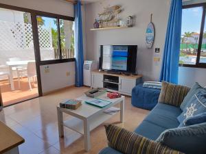 sala de estar con sofá azul y TV en Casa Del Mar - Corralejo Playa, en Corralejo