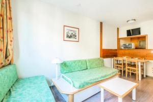 uma sala de estar com um sofá verde e uma mesa em L'Aiguille - maeva Home - 2 Pièces 5 Personnes Confort 39 em Chamonix-Mont-Blanc
