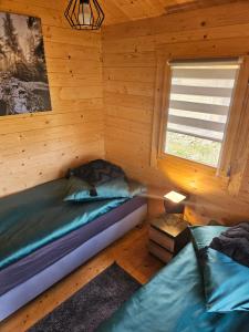 two beds in a log cabin with a window at Domki Letniskowe przy Strażnicy in Wünschelburg