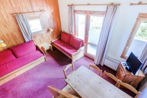 uma sala de estar com um sofá vermelho e uma mesa em Quartier Crève Cœur - maeva Home - Duplex 3 Pièces 8 Personnes Confort 03 em Valmorel