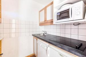 uma cozinha com um lavatório e um micro-ondas em Quartier Crève Cœur - maeva Home - Duplex 3 Pièces 8 Personnes Confort 03 em Valmorel